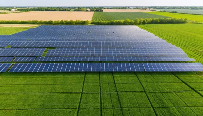 Aerial view of a solar farm in rural Illinois, surrounded by green farmland, symbolizing the integration of renewable energy into local agricultural landscapes.
